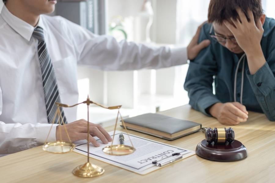 Timeshare owner in Colorado receiving legal advice for contract cancellation, sitting at a desk with attorney, gavel, and scales of justice in view