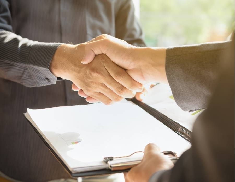 Close-up of a professional handshake over a clipboard, symbolizing a successful timeshare cancellation agreement in Connecticut with TimeshareBeGone.