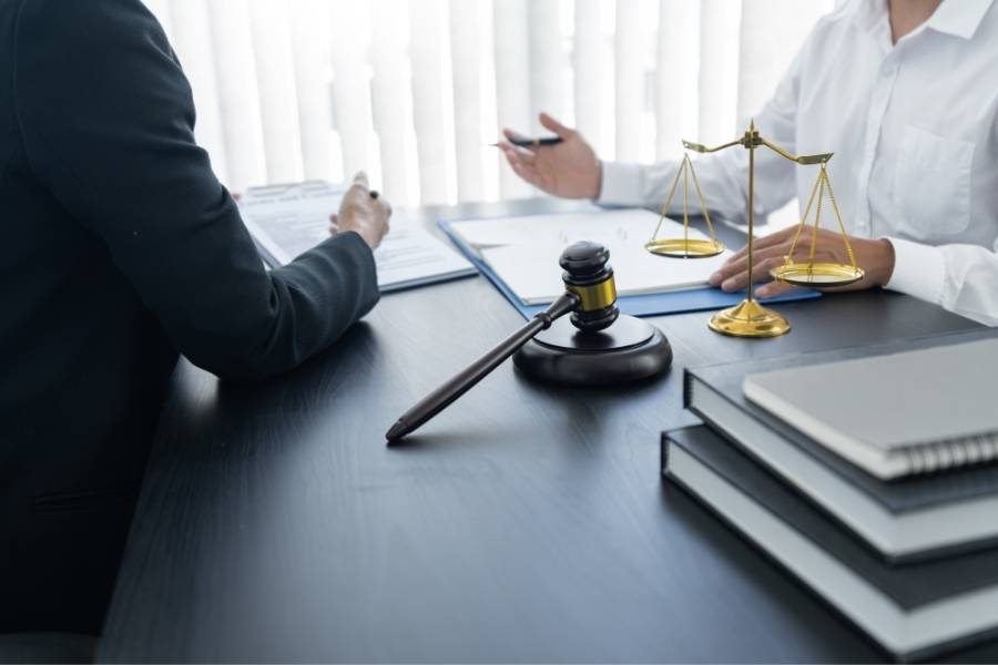 Lawyer providing legal consultation with client in office, featuring gavel, justice scales, and legal documents on desk