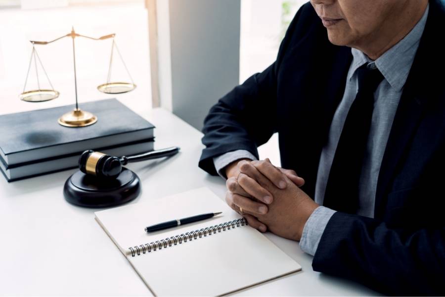 Professional lawyer in suit with gavel, justice scales, and legal notebook during consultation