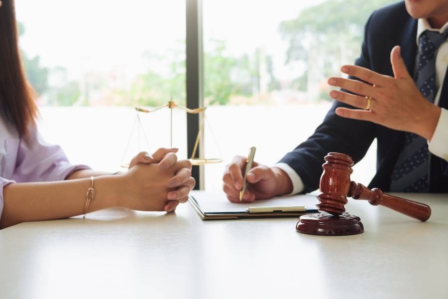 Lawyer discussing legal options with client, gavel and justice scales on desk