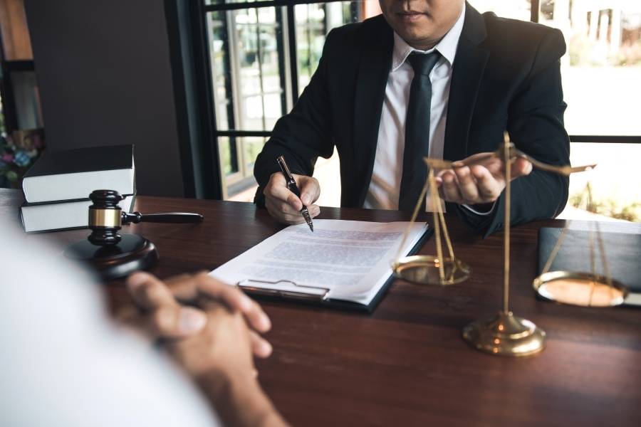 Lawyer explaining legal document details to client with gavel and justice scales on desk