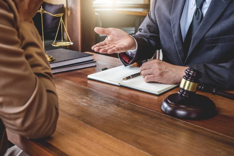 Lawyer providing legal advice to client with gavel and justice scales on office desk