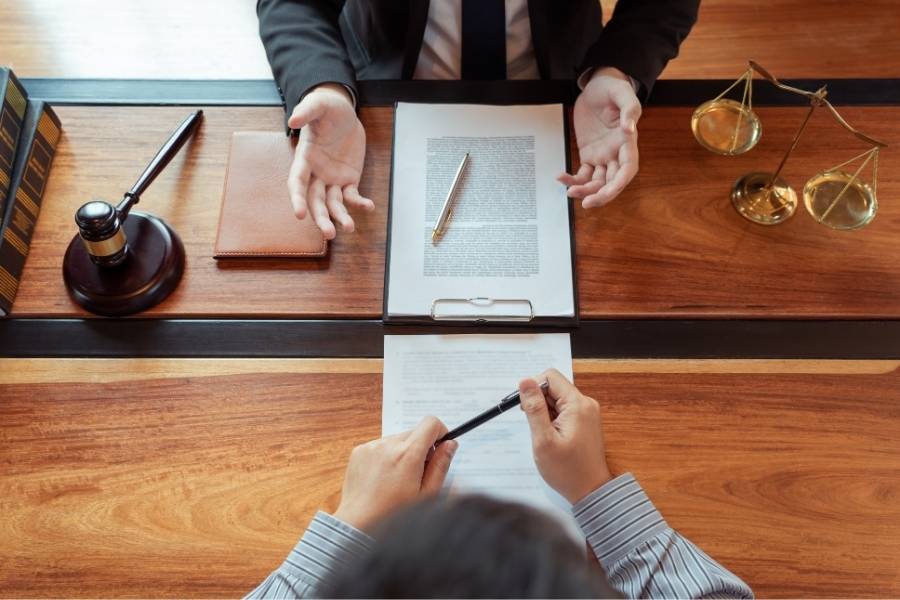 Lawyer consulting with client about legal documents in an office, with gavel, scales of justice, and contract agreement on desk, representing legal services in Ohio.