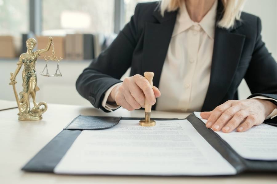 Female lawyer stamping official legal documents for timeshare cancellation in Oklahoma, with Lady Justice statue on desk