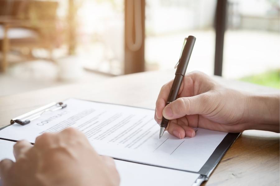 Person signing a contract document—TimeshareBeGone offers trusted timeshare cancellation services in Pennsylvania, helping clients legally exit unwanted vacation property agreements.