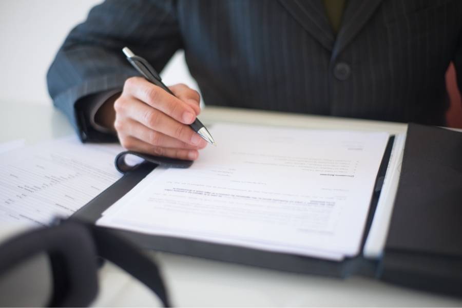 Lawyer reviewing and signing documents for timeshare cancellation in Utah at an office desk.