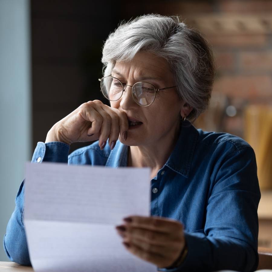 Concerned senior woman reading paperwork about timeshare cancellation in Arizona at home