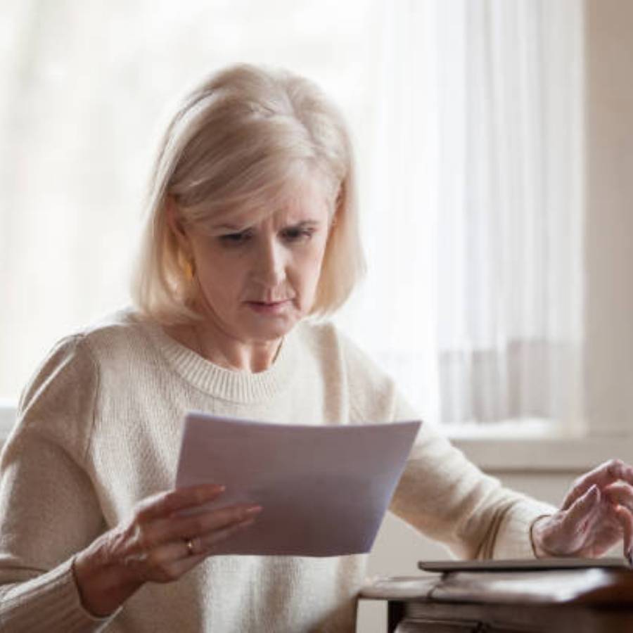 Concerned senior woman reviewing timeshare cancellation documents at home