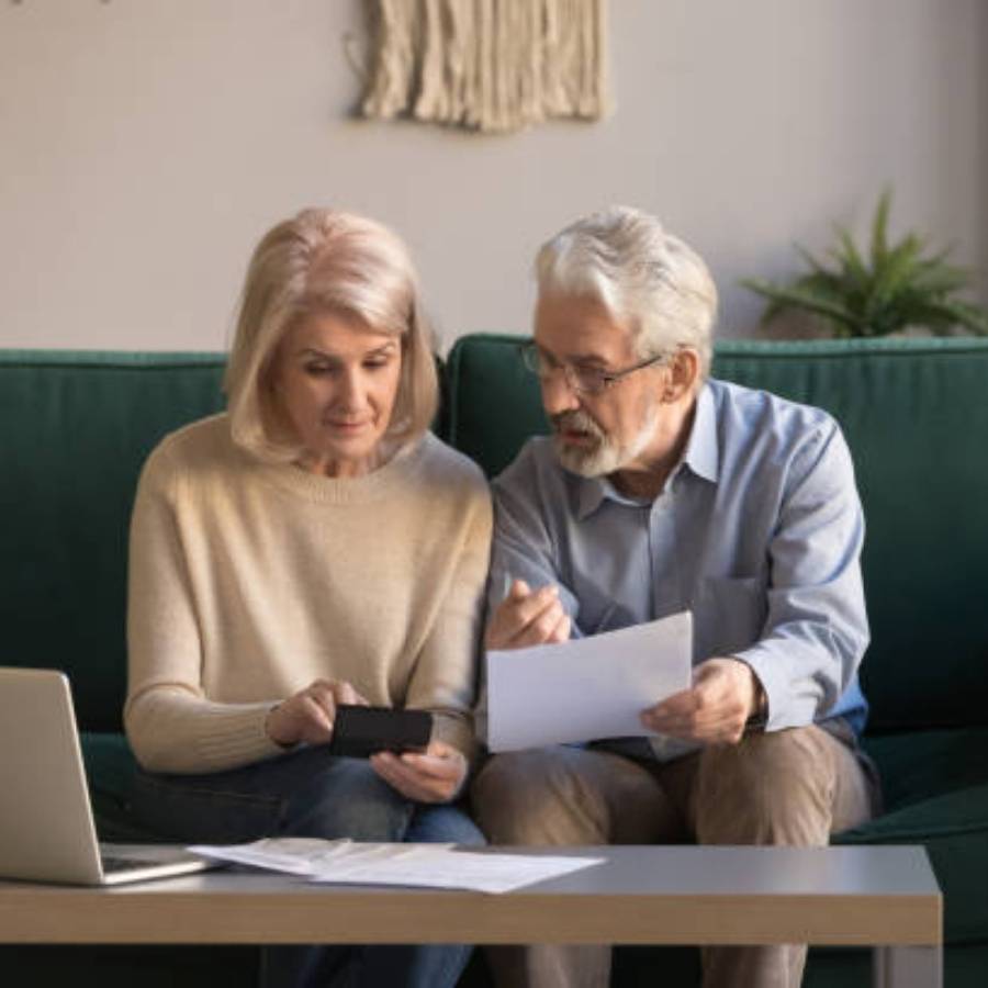 Senior couple reviewing timeshare cancellation paperwork and making payment online at home