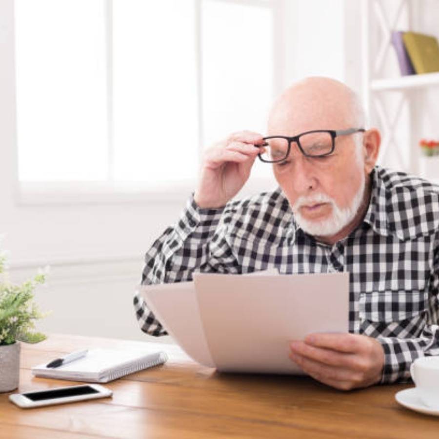 Elderly man reading timeshare cancellation documents at home