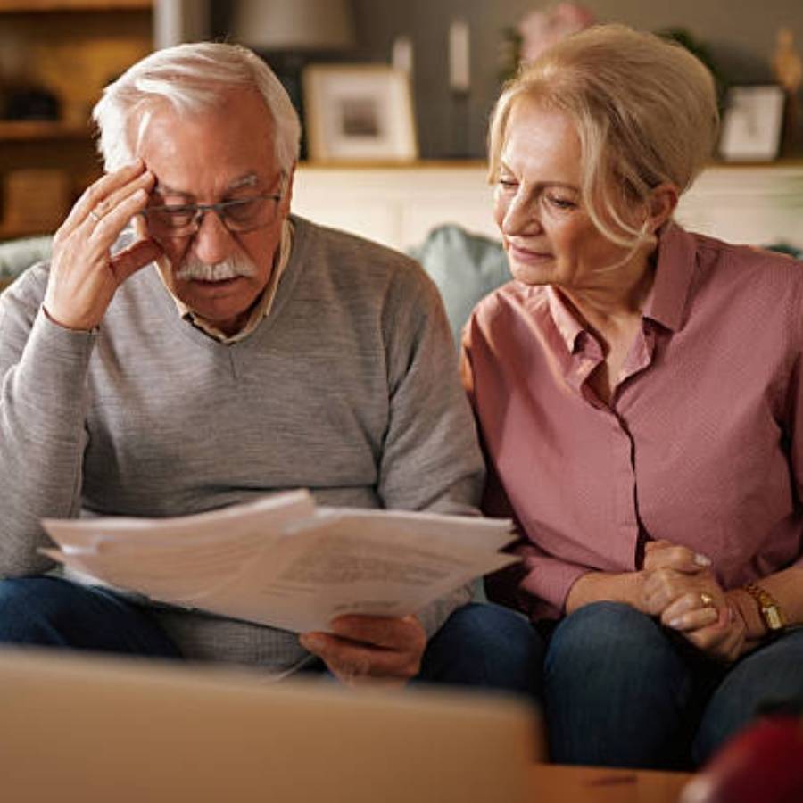 Worried senior couple reviewing timeshare cancellation documents at home