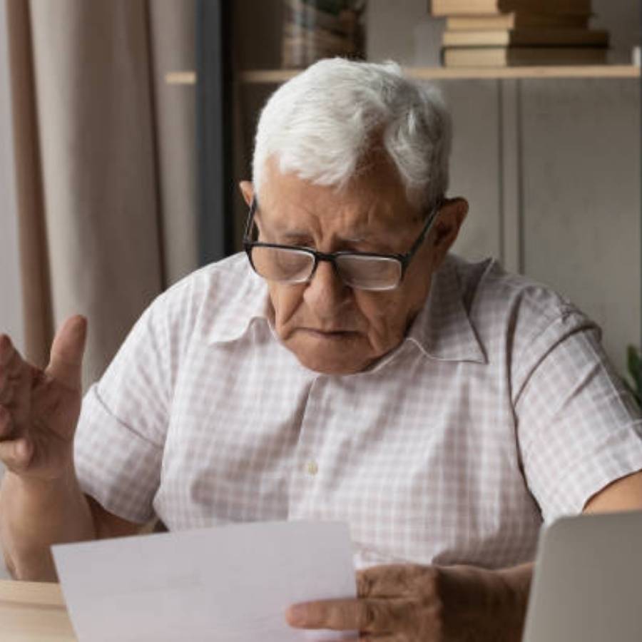 Elderly man reading timeshare cancellation paperwork at home