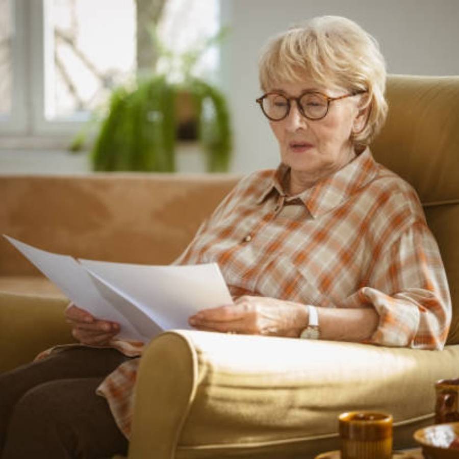 Senior woman reading timeshare cancellation paperwork while sitting at home