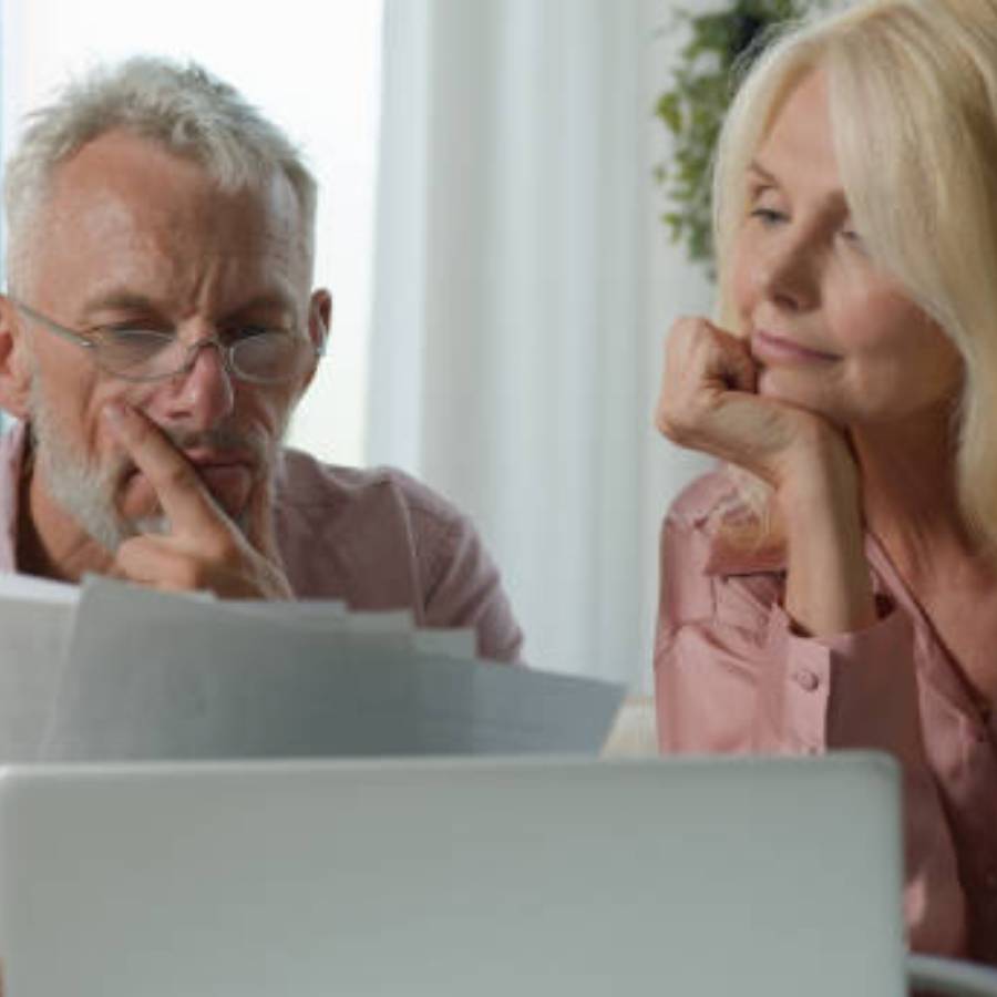 Senior couple reviewing timeshare cancellation documents on laptop at home