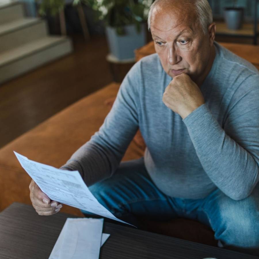 Concerned senior man reviewing timeshare contract documents at home, considering timeshare cancellation options in Ohio