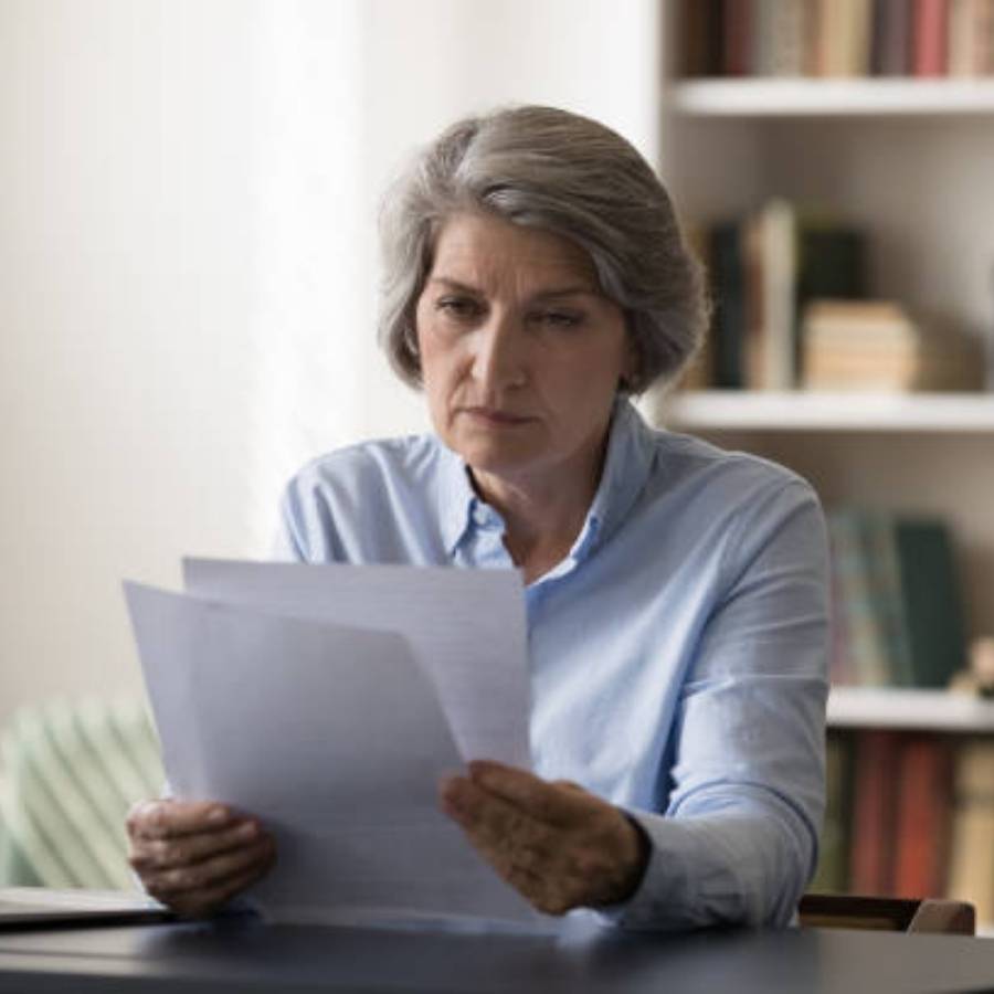 Focused senior woman reading timeshare cancellation paperwork at home in Oklahoma
