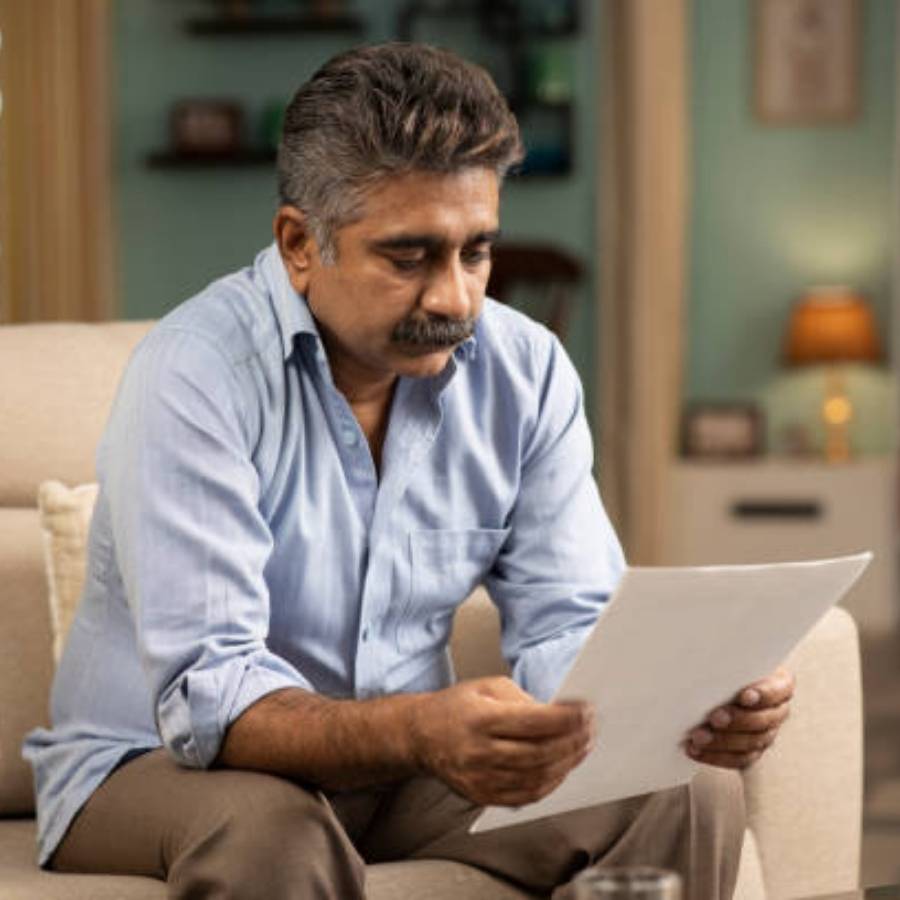 Concerned man reading paperwork about timeshare cancellation in Utah while sitting at home.