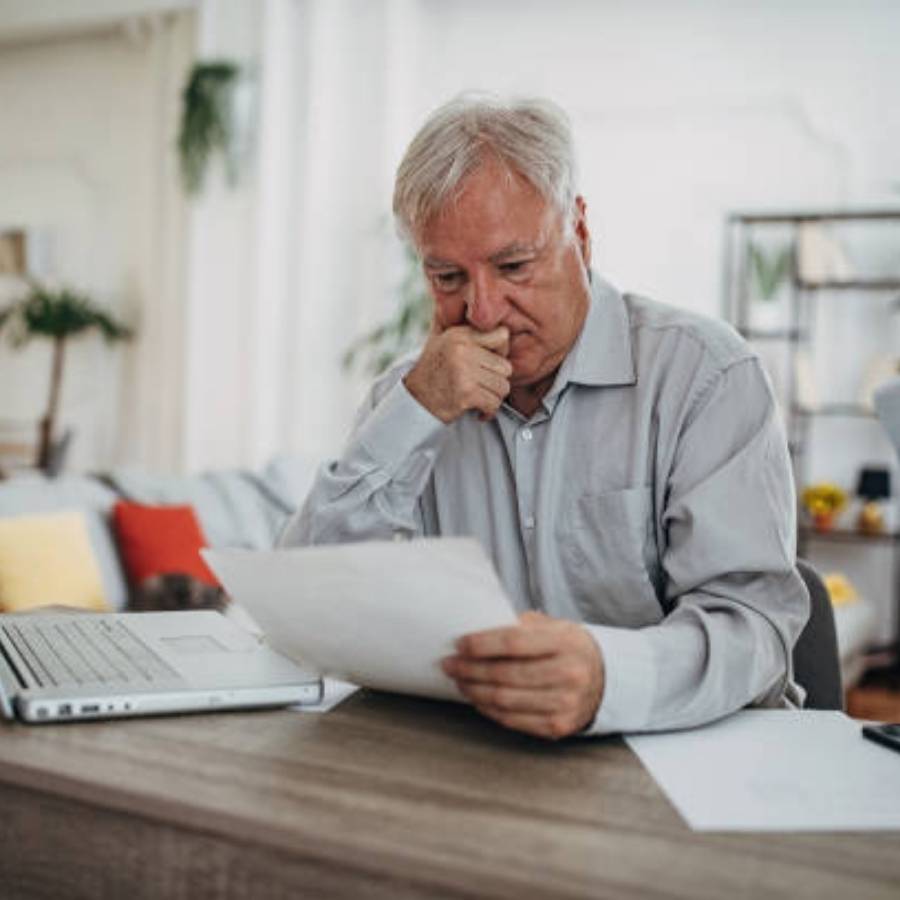 Worried senior man reviewing timeshare cancellation paperwork at home in West Virginia, considering legal options to end contract