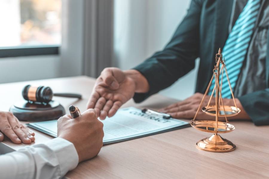 Lawyer providing legal advice as a client signs a contract, with gavel and justice scales on the desk in Tampa, Florida.
