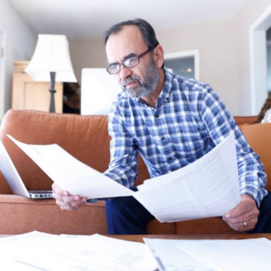 Middle-aged man carefully reviewing timeshare cancellation paperwork at home in Augusta, Georgia