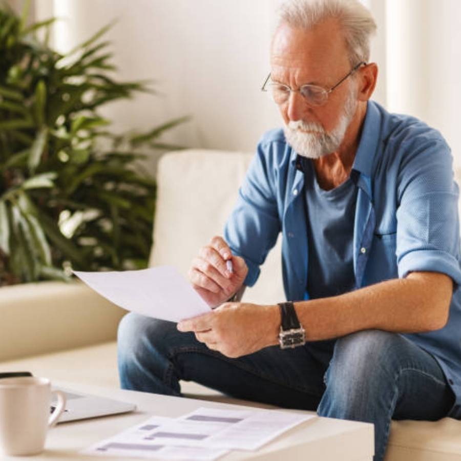Senior man reading timeshare cancellation paperwork at home in Columbus, Georgia
