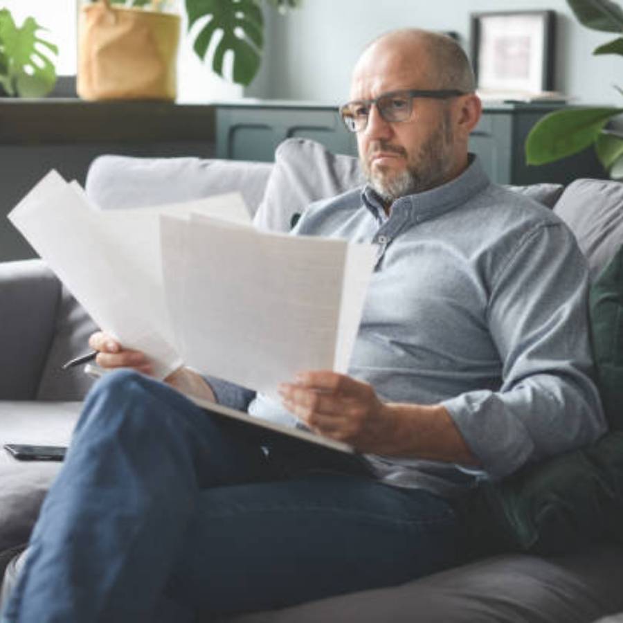 Middle-aged man reviewing timeshare cancellation documents at home in Durham, North Carolina