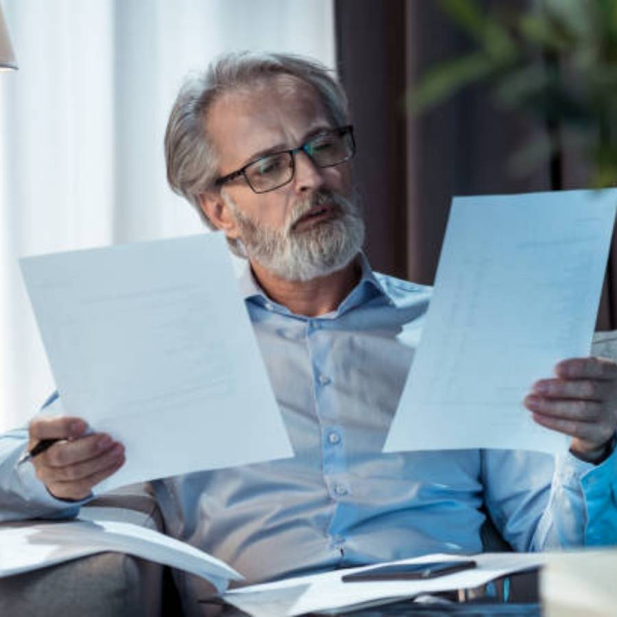 Older man reviewing timeshare cancellation paperwork at home in Greensboro, North Carolina.