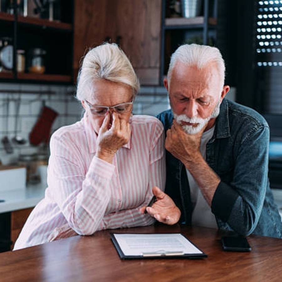 Worried senior couple reviewing timeshare cancellation documents at home in Orlando, Florida