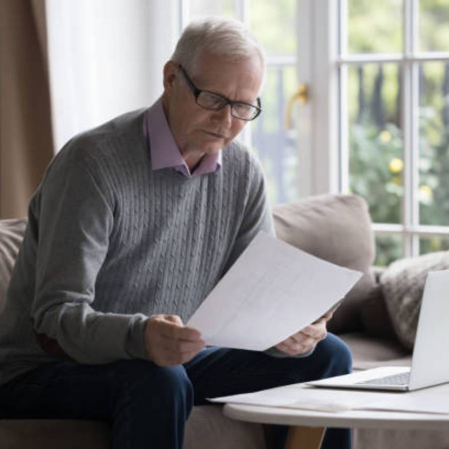 Senior man reviewing timeshare cancellation documents on laptop at home in Raleigh, North Carolina