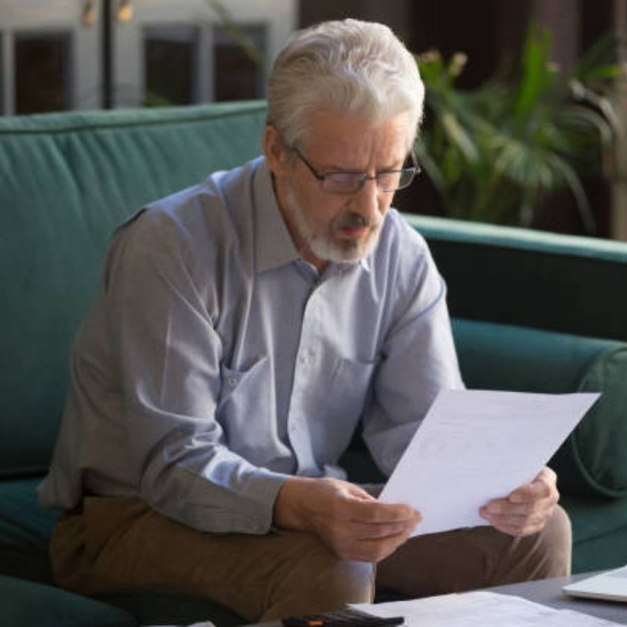 Senior man carefully reading timeshare cancellation documents at home in Wilmington, North Carolina